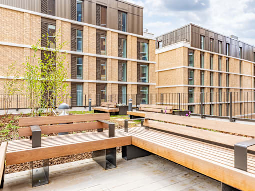 A modern building with a tree and benches in front.