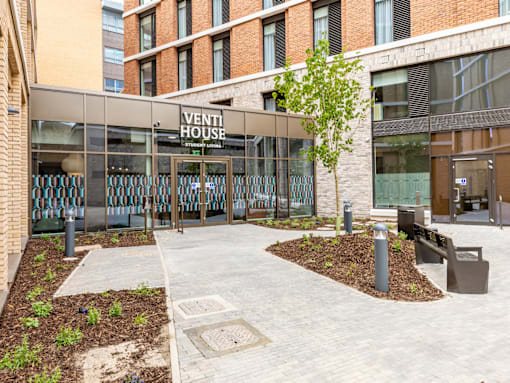 A building with a glass facade and a sign that says "VENTI HOUSE" is shown.