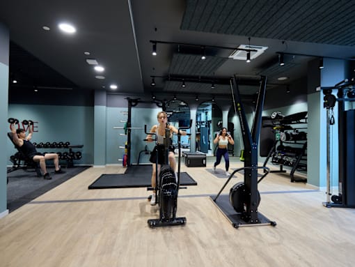 A gym with people exercising and fitness equipment.