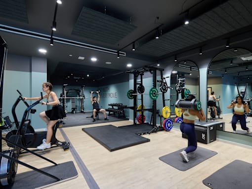 A gym with people exercising and a woman on an exercise bike.