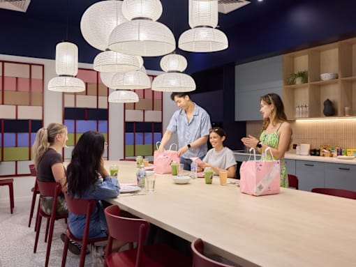 A group of people are gathered around a table in a room with hanging lights.