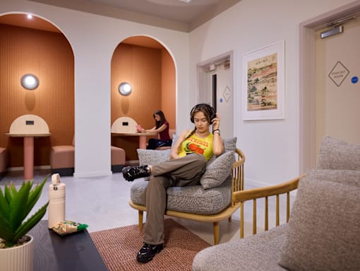 A woman is sitting on a chair with headphones on.