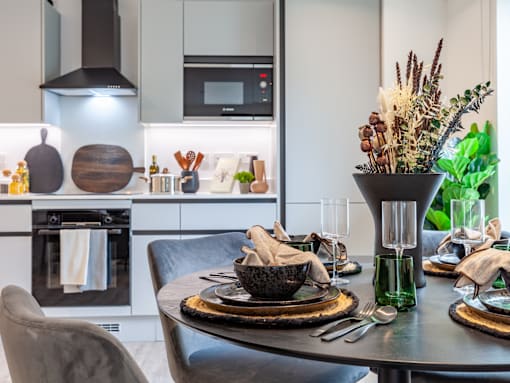 A modern kitchen with a dining table set for two.