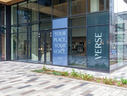 A glass building with a sign that says "your place, your voice" on it.