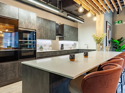 A long white table with brown chairs in front of a grey counter.