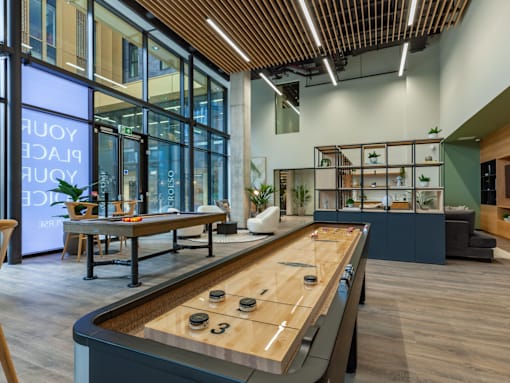 A shuffleboard table is in the middle of a room with a couch and a chair.
