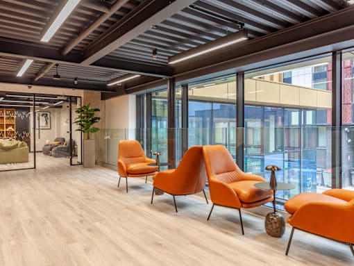 A room with orange chairs and a wooden floor.