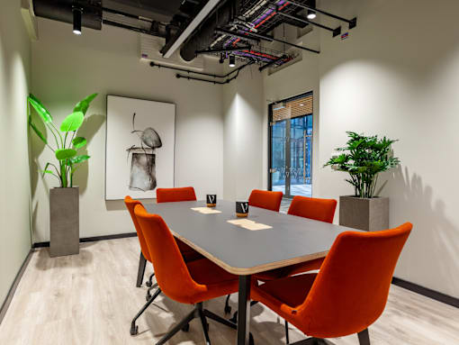 A conference room with a table surrounded by orange chairs.