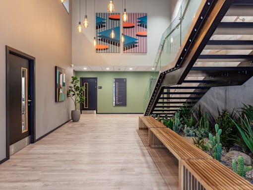A hallway with a glass staircase and wooden floors.