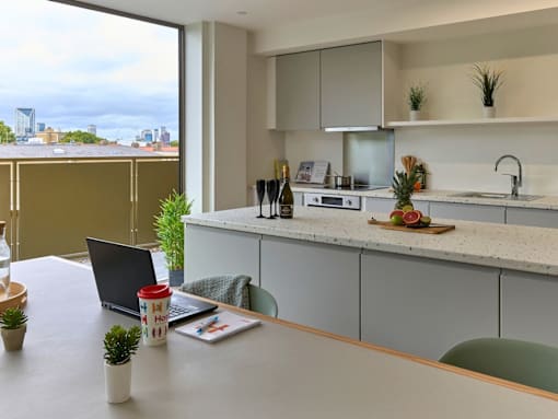 A modern kitchen with a laptop on the table.