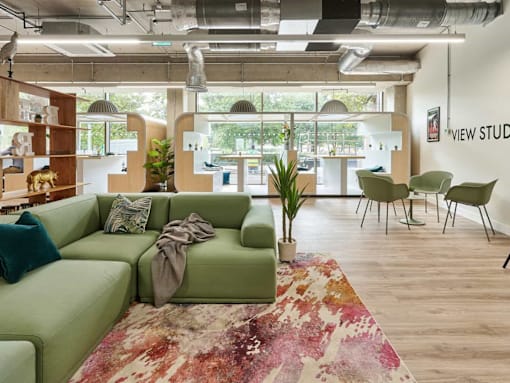 A living room with a green couch and a rug.
