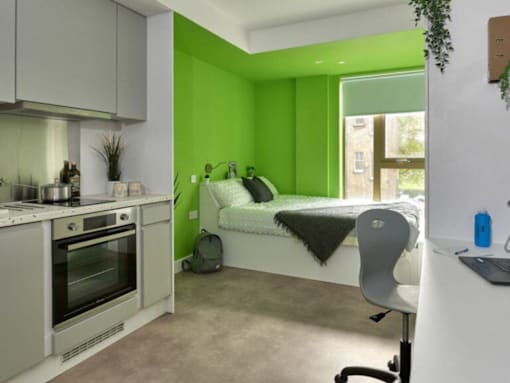 A modern kitchen with a green wall and a white chair.
