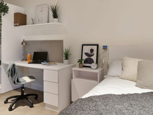A small bedroom with a bed, desk, and chair.