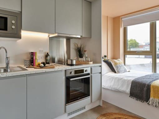 A modern kitchen with a bed in the background.