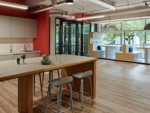 A modern kitchen with a wooden table and bar stools.