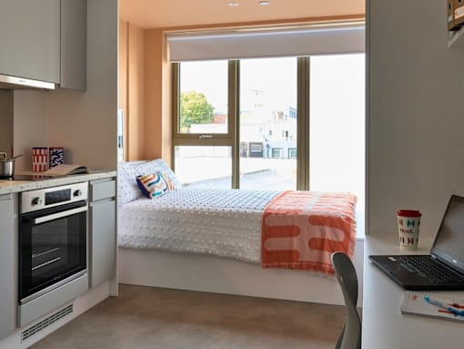 A modern kitchen with a bed in the corner.