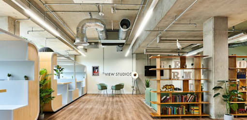 A modern office space with a wooden floor and exposed ceiling pipes.