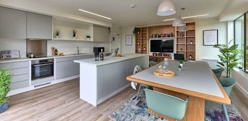 A modern kitchen with a wooden island and a dining table with chairs.