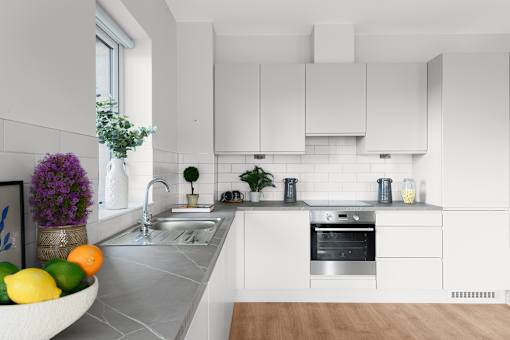 a white kitchen with white cabinets and a bowl of fruit