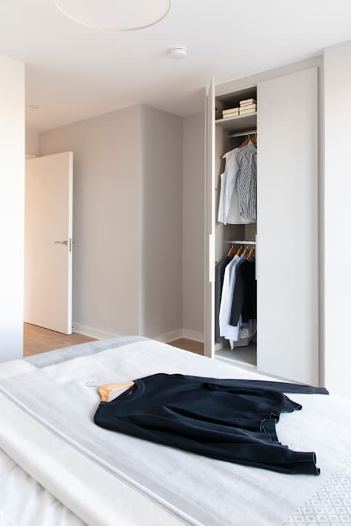 a bedroom with a bed and a closet with clothes on it
