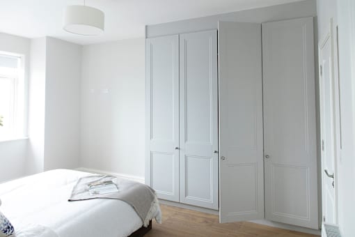 a bedroom with white closet doors and a white bed