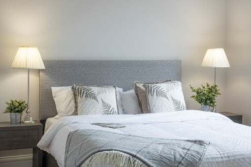 a bedroom with a large bed with pillows and a grey headboard
