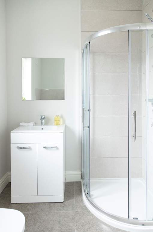 a small white bathroom with a shower and a sink