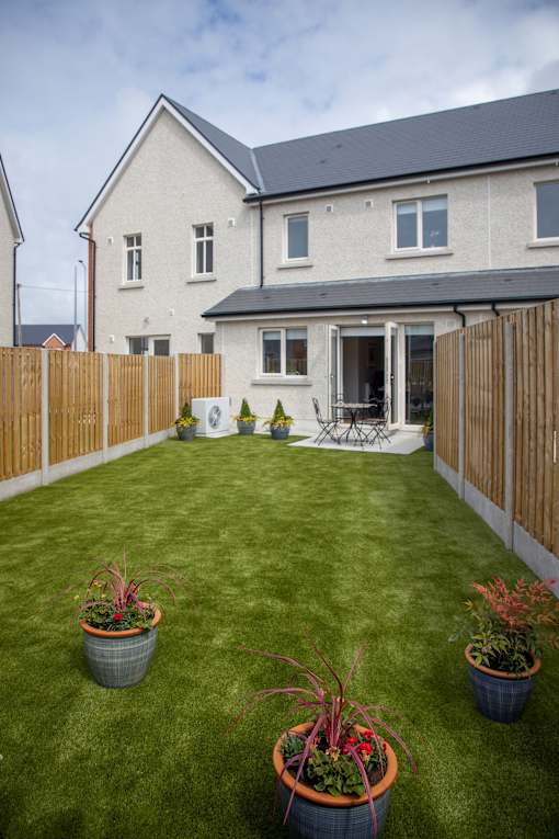a back garden with potted plants and a house