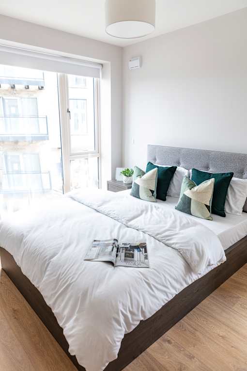 a bedroom with a large bed with white sheets and green and white pillows