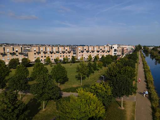 an aerial view of a park with trees and buildings in the background