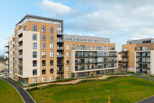 a large apartment building with a green field in front of it