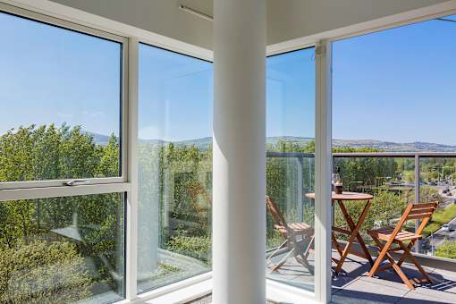 a room with large windows and a table and chairs on a balcony