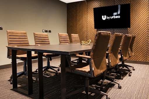 a conference room with a table and chairs and a television