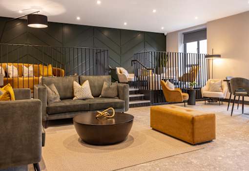 a living room with couches and chairs and a staircase
