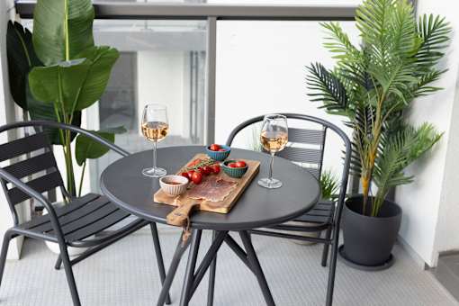 a small patio with a table and chairs and glasses of wine