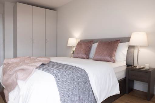 a bedroom with a white bed and a grey blanket and pillows
