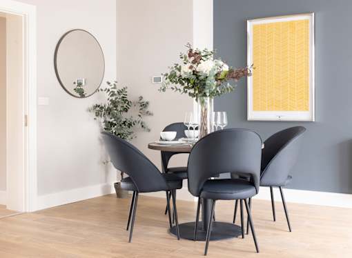 a dining room with a table and chairs and a mirror on the wall