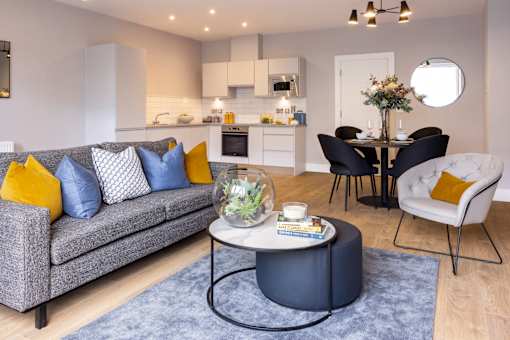 a living room with a couch and a table in front of a kitchen