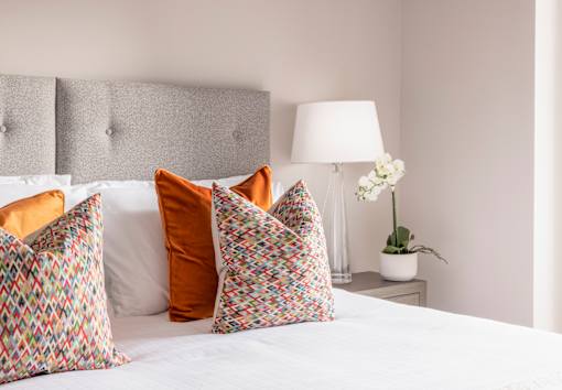 a bed with pillows and a nightstand with a lamp and a plant