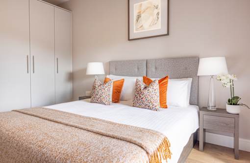 a bedroom with a white bed and orange pillows