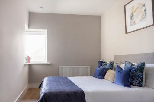 a bedroom with a bed with blue pillows and a window