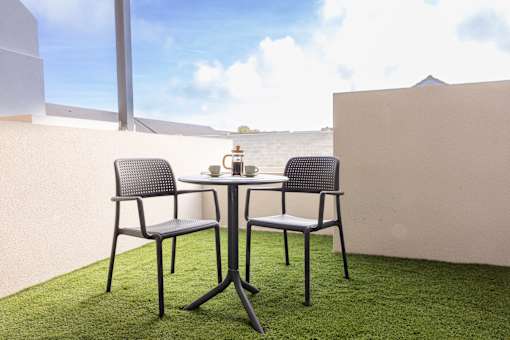 a terrace with a table and chairs on a grass