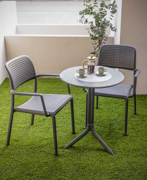 a patio table with two chairs and a coffee cup on it
