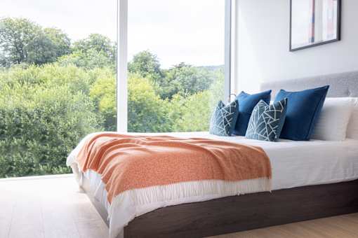 a bedroom with a large window and a bed with pillows