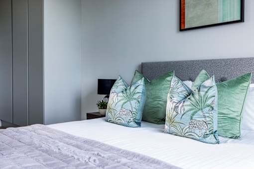 a bedroom with a bed with green and white pillows