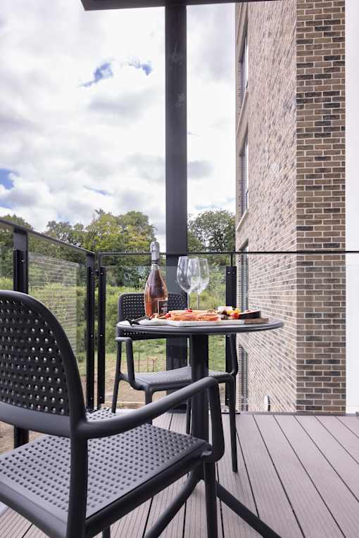 a balcony with a table and chairs and a bottle of wine on it