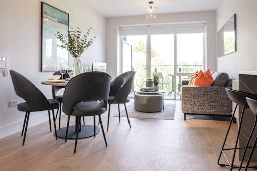 a living room and dining room with a table and chairs and a balcony