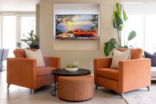a living room with orange chairs and a table and a painting on the wall