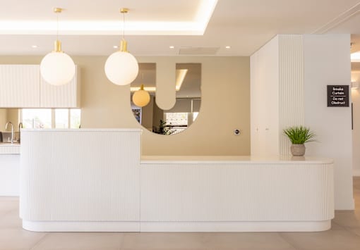 a white reception desk with a large circular mirror on the wall