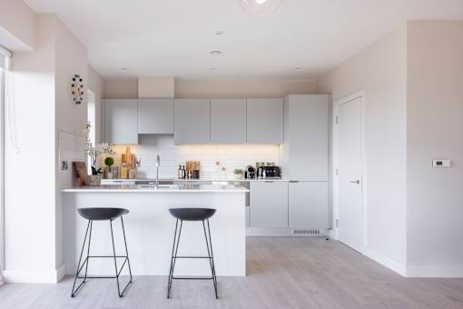 a kitchen with white cabinets and a white island with two bar stools